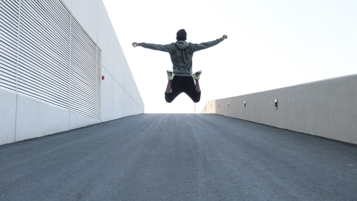 Man jumping on urban road with arms spread wide in Dubai, showcasing freedom and energy.